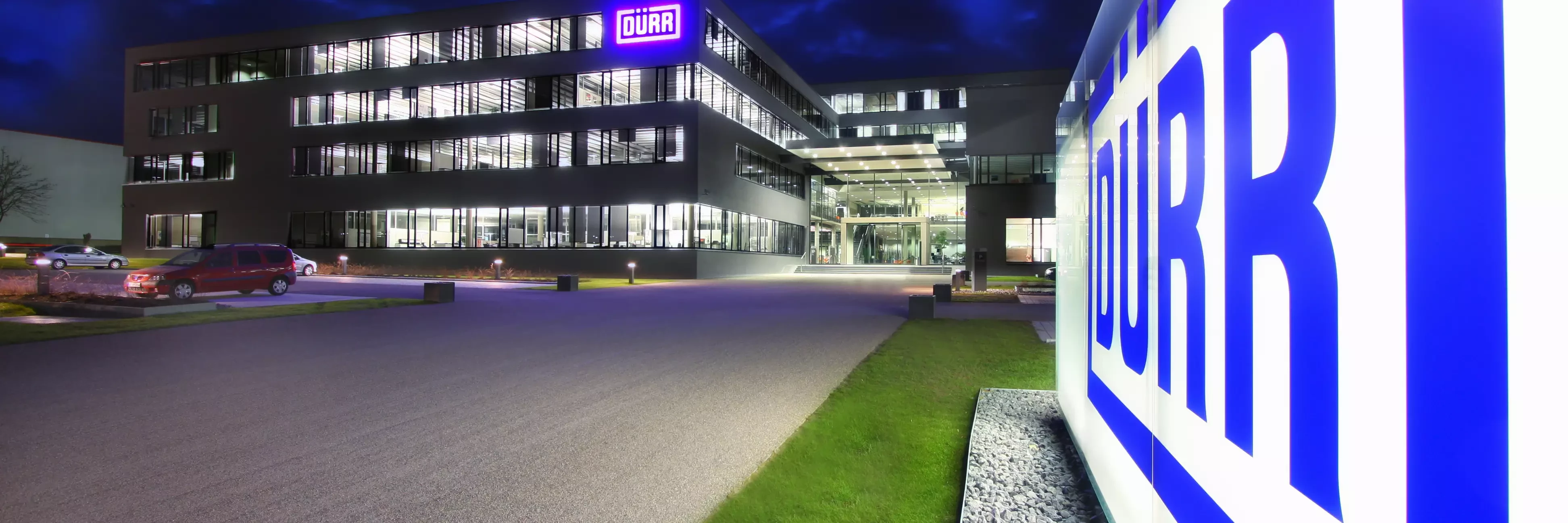 Dürr location headquarters in germany at night viewing the shining logo in the front of the building.